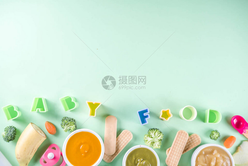 婴幼儿食品有蔬菜水果泥绿色橙色黄色的碗西兰花胡萝卜香蕉苹果用品和玩具绿色背景平躺顶图片