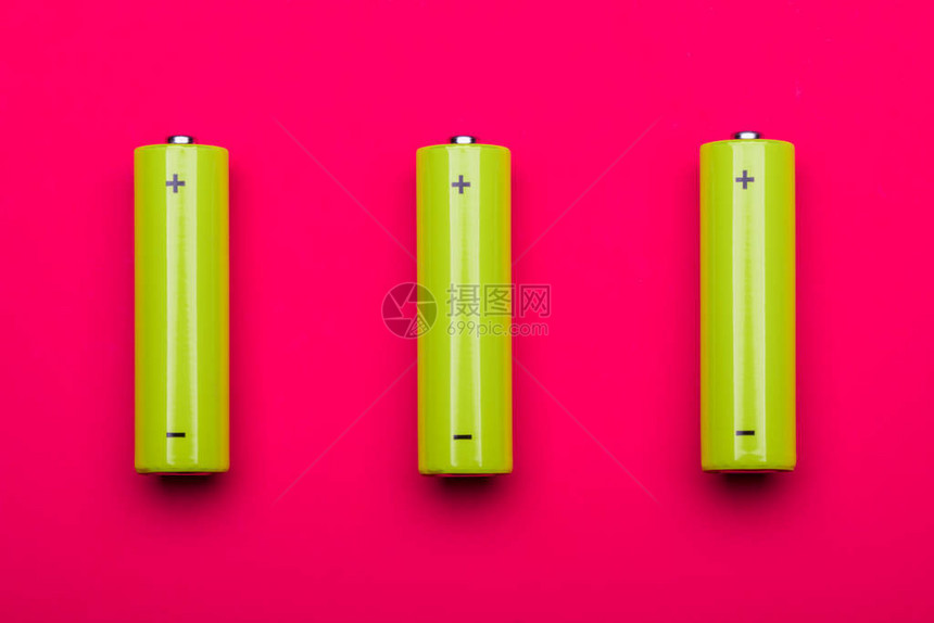 3个黄绿色AA碱电池或粉色背景可充电的NiMH电池图片