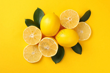 黄色背景上多汁的柠檬和叶子顶视图图片