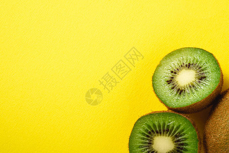 Kiwi水果半切成生机勃的平原黄色背景复制背景图片