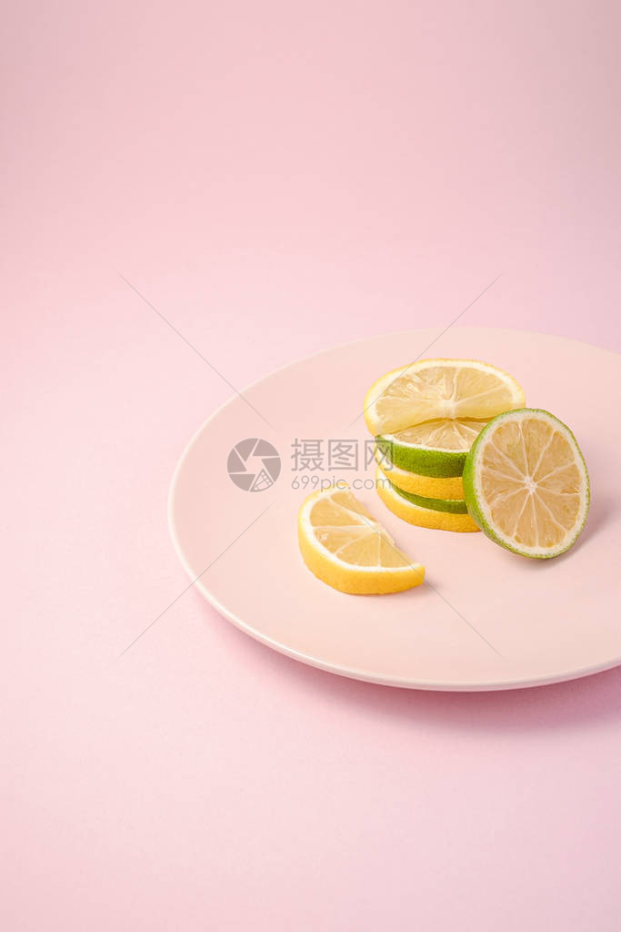 粉红色盘子上堆叠的鲜新美味的柠檬和柠檬柑橘水果切片图片