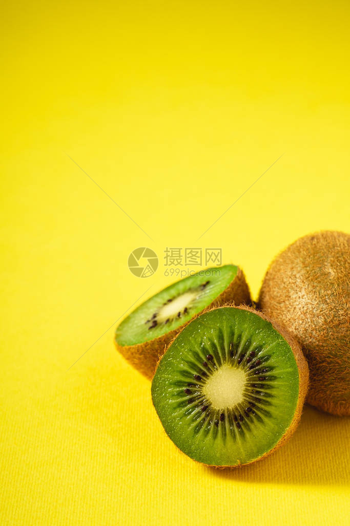 Kiwi水果半切成生机勃的平原黄色背景复制空图片