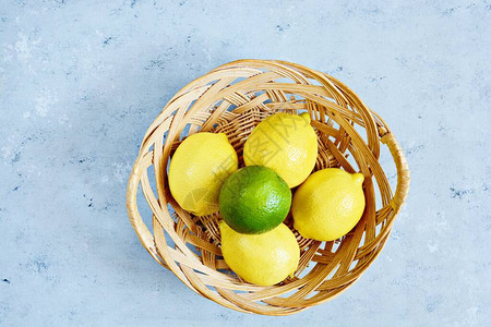 蓝底的篮子里新鲜柠檬和石图片