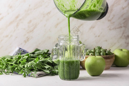 绿色的冰雪从玻璃搅拌机碗倒入仙人掌形状的玻璃杯中健康原始食图片