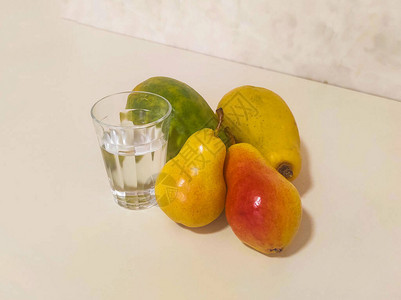 一杯水和黄水果木瓜和梨子在背景图片