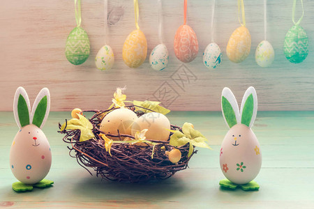 复活节兔子玩具巢中的鸡蛋和老式木背景上的一排挂鸡蛋复活节的心情有趣图片