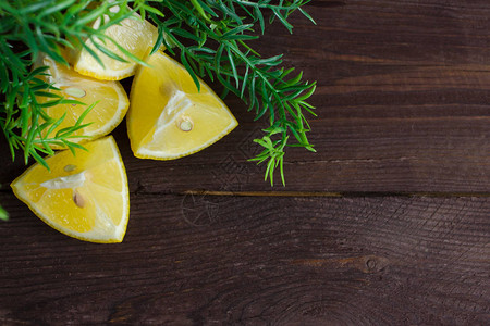 深色木质背景上的柠檬和绿叶小枝背景图片