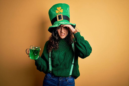 美丽的卷发女人戴着帽子喝着绿色饮料罐图片