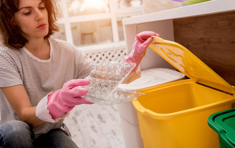 年轻女孩在厨房分拣垃圾回收的概念图片