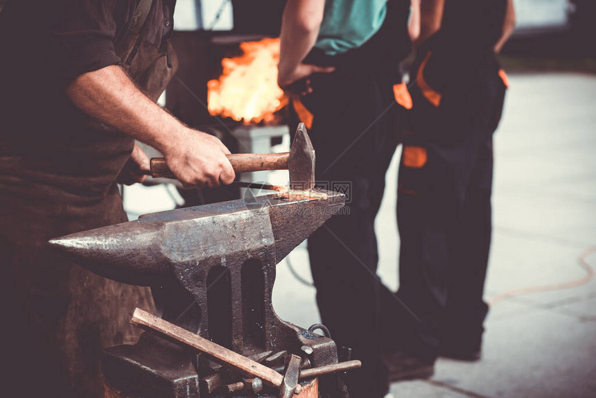 铁匠用火花烟手工锻造铁砧上的熔融金属图片