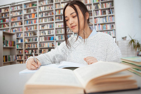 亚裔年轻女学生在图书馆的笔记本上图片