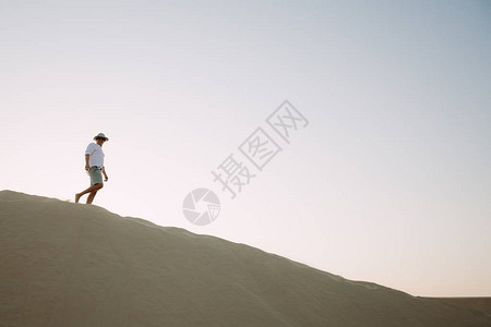 一个人在沙漠的沙丘上行图片