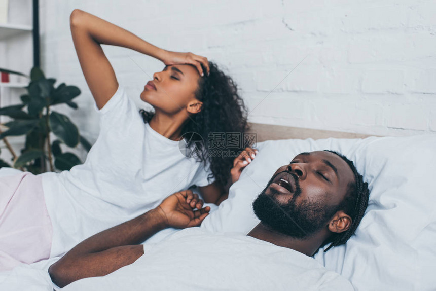 年轻的非洲裔美国妇女躺在打鼾的丈图片