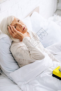 生病的老年妇女在床上头痛图片