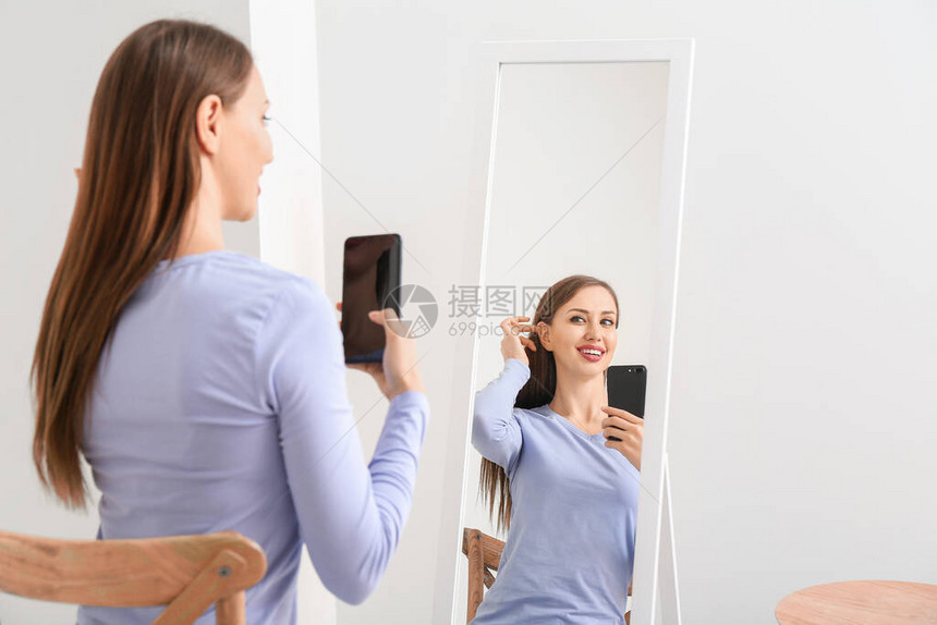 美丽的年轻女人在家里镜子前图片
