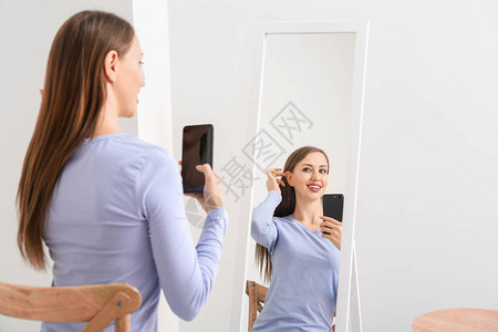 美丽的年轻女人在家里镜子前背景图片