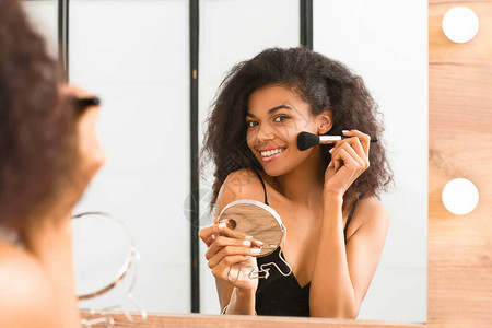 美丽的非洲裔美国女人在镜子前化妆背景图片