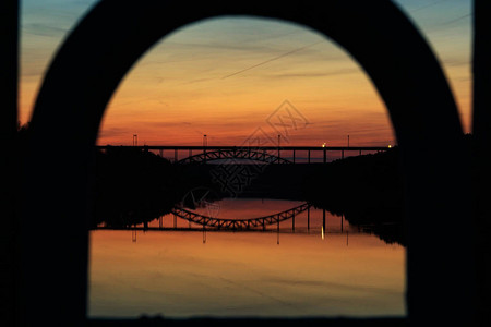 日落时横跨河面穿过拱门的铁路桥视线前景色环图片