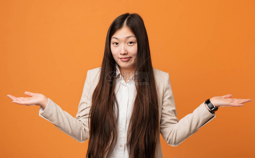 年轻的女商人在质疑姿态中怀疑和挥舞他的肩膀图片