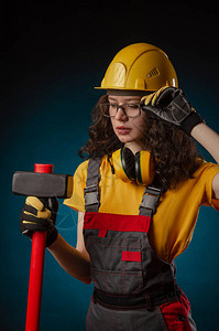 戴着大锤的建筑头盔和工作服的女孩图片