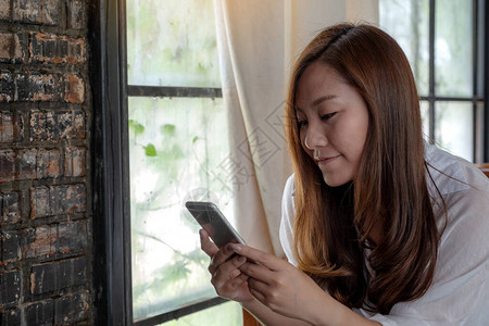 使用和触摸智能手机的亚洲女抱持使用和触碰智能电图片