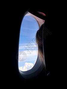 后面的乘客向飞机窗外看图片