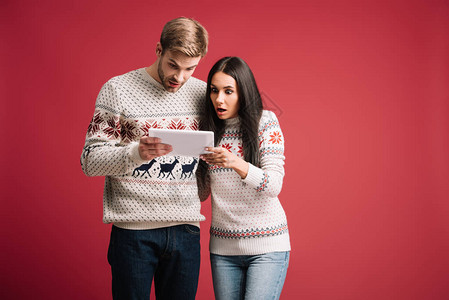 穿着冬季毛衣的一对奇异夫妇使用数字平板电脑图片