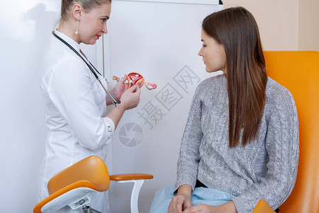 医生妇科医生在医务室与一位坐在橙色椅子上图片