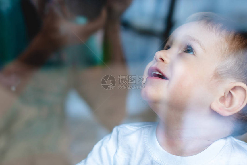 美丽可爱的男婴用反射看着窗玻璃图片