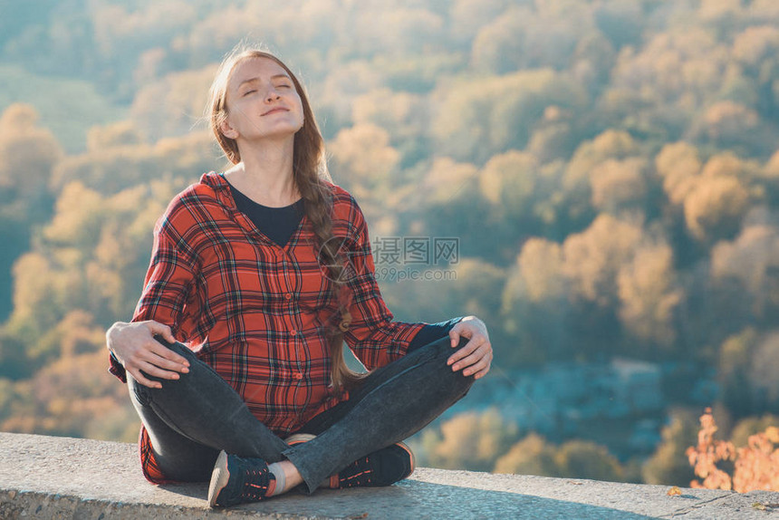 孕妇坐在山上眼睛闭着沉思秋森林背景图片