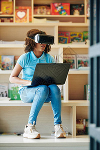 卓尔书店穿着休闲服的少女坐在现代学校图书馆使用VR眼镜和笔记本背景