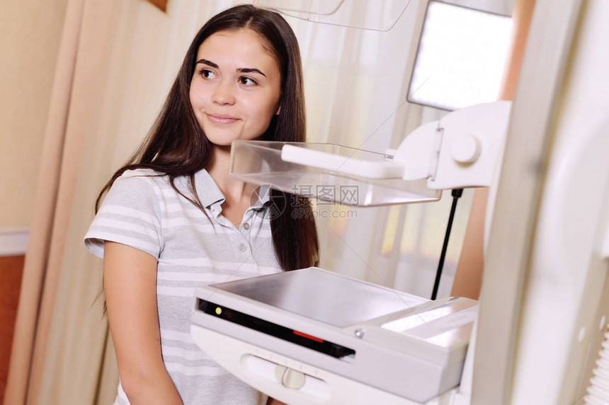 一个漂亮的年轻女孩靠近乳房X光检查仪一台光机图片