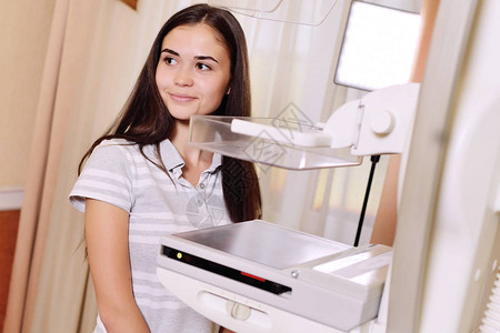 投光机一个漂亮的年轻女孩靠近乳房X光检查仪一台光机背景