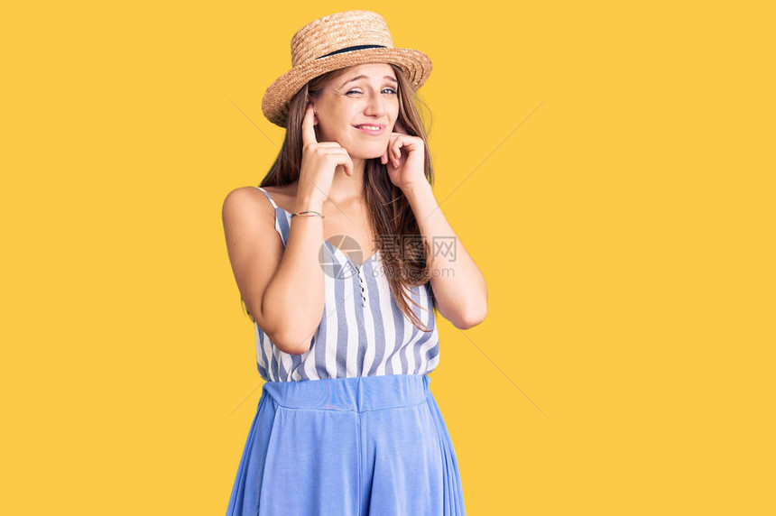 穿着暑期帽子的年轻金发女子用指头遮住耳朵图片