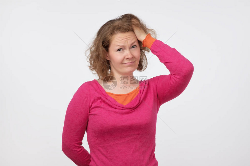 穿着粉红色毛衣的年轻欧洲女人带着疑问在镜头前看图片