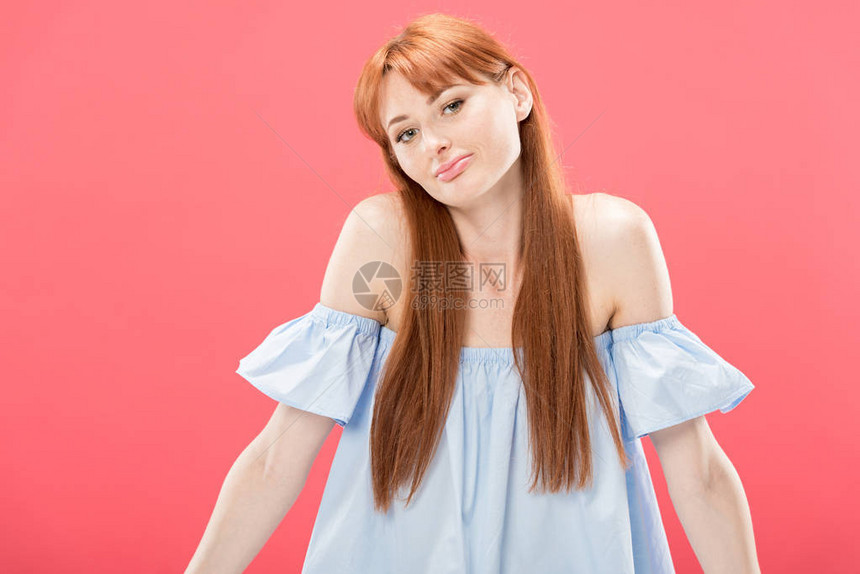 红发女红发年轻女人看着镜头并举着在粉红色上孤图片
