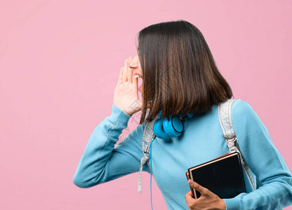 带着蓝色毛衣和耳机的年轻女学生女孩大喊叫图片