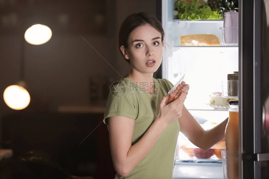 害怕女人在晚上选择冰箱附近的美味不健康食物时被抓图片