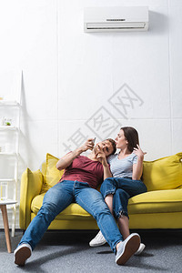 年幼的一对混乱的年轻夫妇与在家中发热空调图片