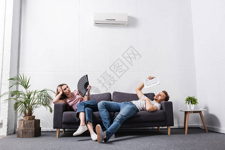 带手风扇的年轻夫妇和家里发热空调机坏图片