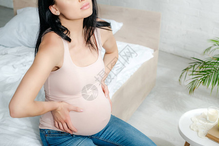 担心怀孕妇女在卧室内疼痛和触摸肚子图片