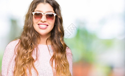 年轻美女穿着太阳镜和粉红色毛衣图片