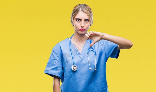 年轻漂亮的金发医生外科医生护士女人在孤立的背景下看起来不快乐和愤怒图片