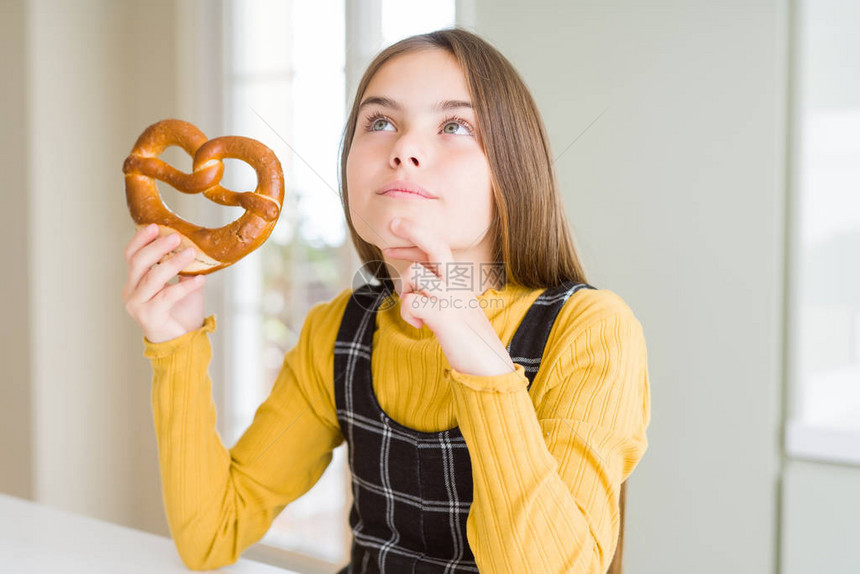 美丽的年轻女孩子吃德国小吃点心咸脆饼严肃的面对现实思考问题图片