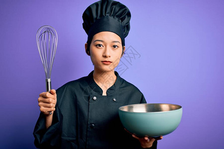 年轻漂亮的厨师女穿着炊具制服和帽子图片