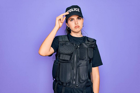 身穿紫色背景安全防弹背心制服的年轻女警担心和强调手放在额头上的问题图片