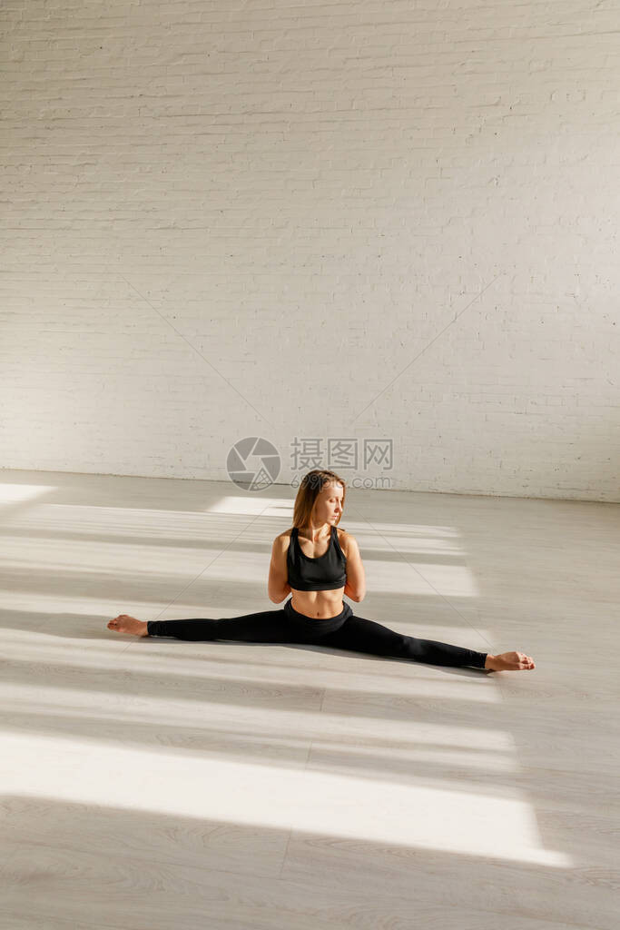 灵活的女人在地板上做麻线伸展图片