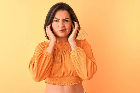 年轻漂亮的女人穿着休闲t恤站在孤立的橙色背景上图片