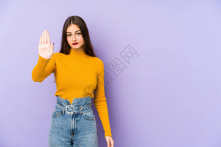 在紫色背景下被孤立的年轻天主教女站在伸展的手边展示了停止信图片
