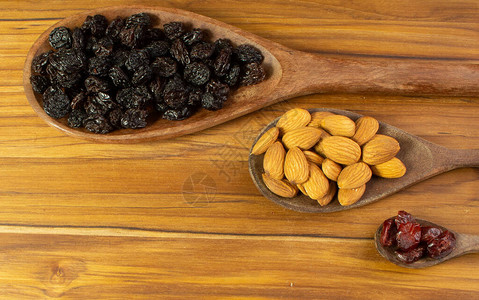 三勺装满杏仁小红莓和葡萄干图片